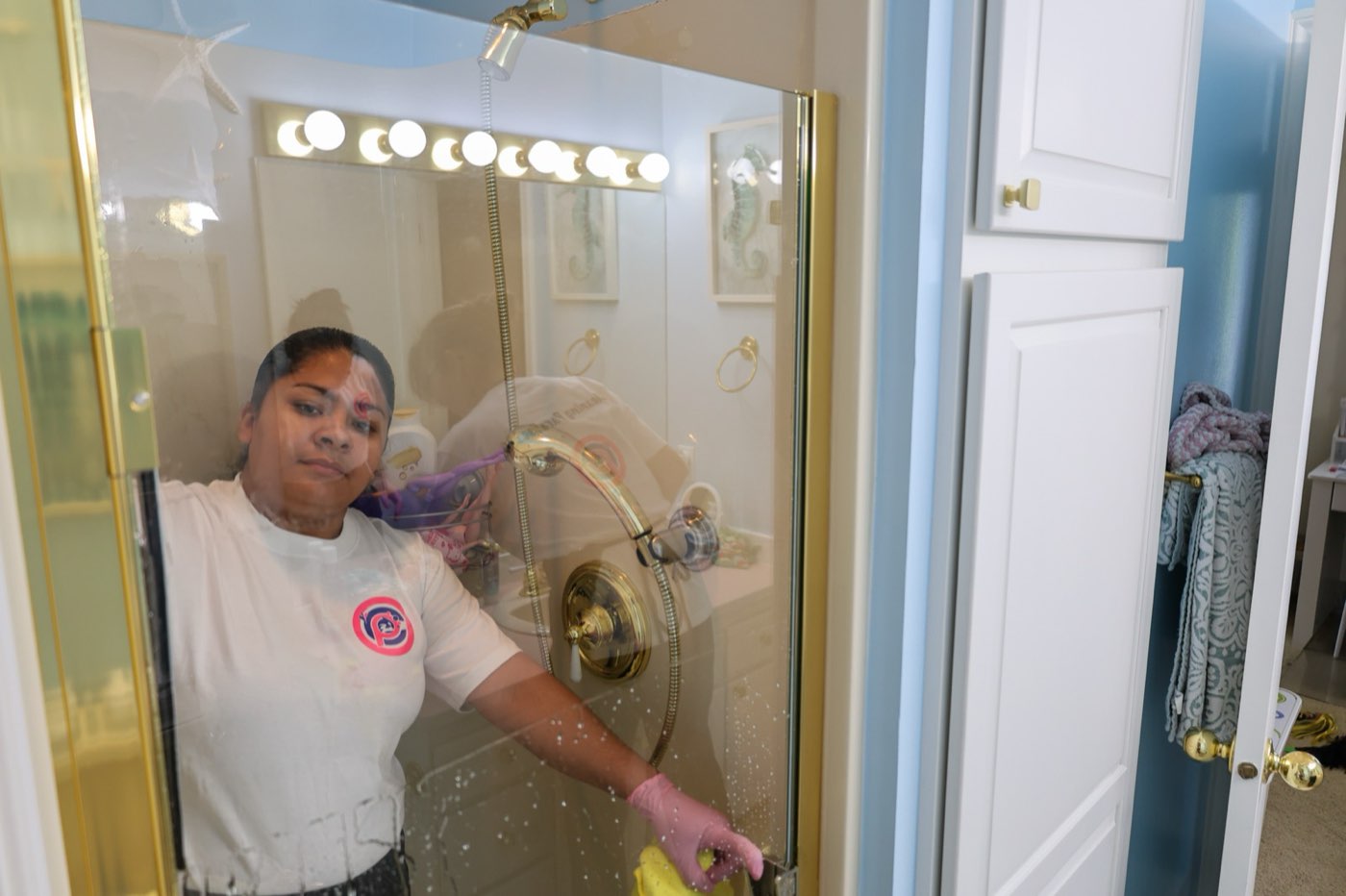 Maid polishing a glass shower door during a deep cleaning in Seattle, WA